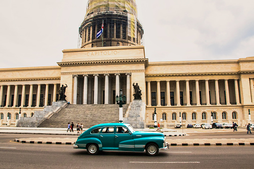 Havana, Cuba - July 06 2018 : The Parliament building of Cuba. An old american retro car is passing by.