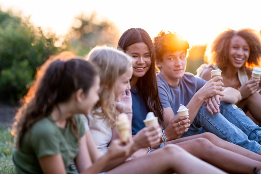 A diverse group of teens eat ice cream together.