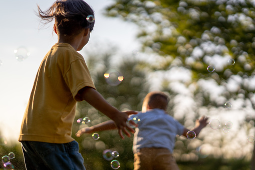 A child plays with bubbles that are cast in the warm glow of the evening sun.