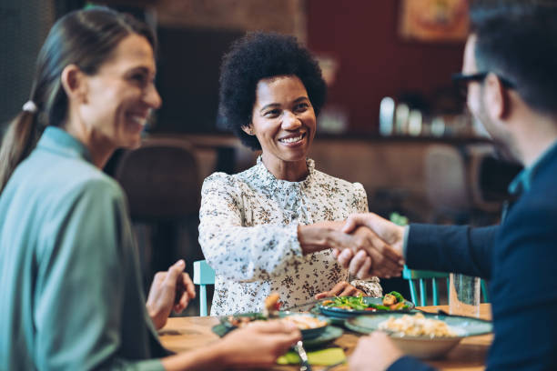 istock Business persons shaking hands across the table during dinner 1439330616