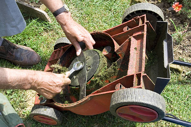 Close-up of hands fixing an overturned lawnmower with wrench Correcting the lawn mower knife blade stock pictures, royalty-free photos & images