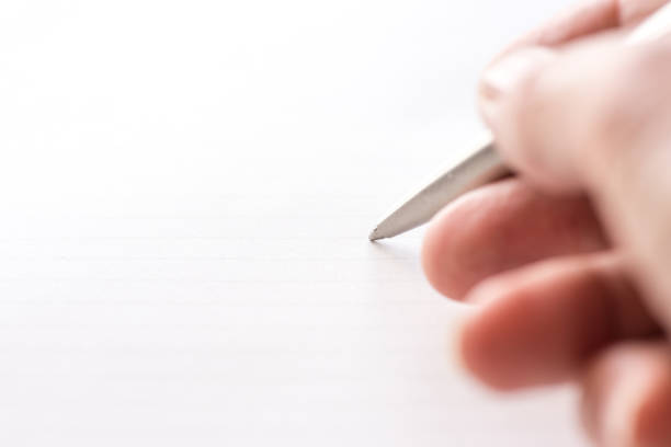 woman's hand holding ballpoint pen against blank lined paper - writing letter correspondence women imagens e fotografias de stock