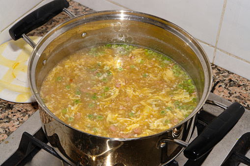 Seasonal vegetable soup with potatoes, ham, onions, eggs, peas, corn, and tomatoes