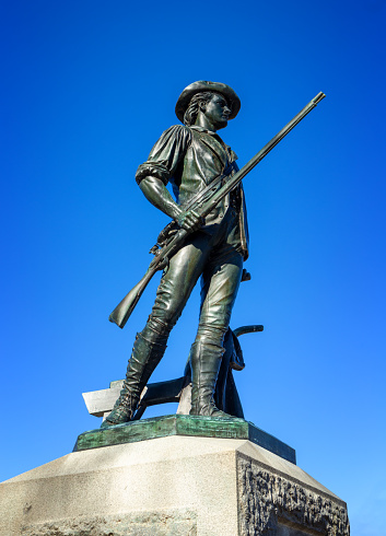 Concord, Massachusetts, USA - November 3, 2022: Close-up of the Minute Man statue at Old North Bridge. The statue was unveiled and dedicated during the celebrations for the centennial of the Concord Fight on April 19, 1875. The statue was cast from melted down Civil War cannons. On April 19, 1775, the first day of the American Revolutionary War, provincial minutemen and militia companies engaged British Army troops at this location. The significance of the historic events inspired Ralph Waldo Emerson to refer to the moment as 