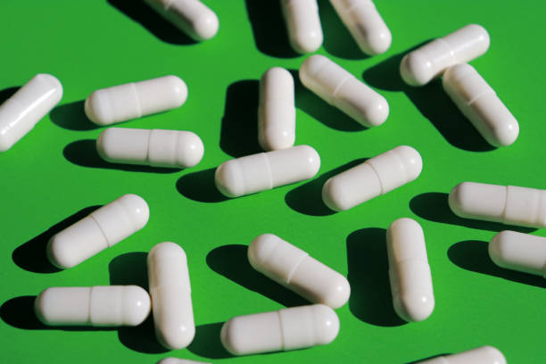 istock white pills capsules and bottle on green background 1439363234