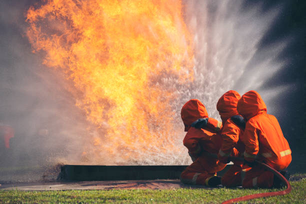 istock Firefighter Rescue training in fire fighting extinguisher. Firefighter fighting with flame using fire hose chemical water foam spray engine. Fireman wear hard hat, safety suit uniform for protection 1439365045