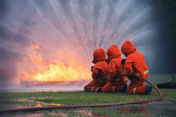 istock Firefighter Rescue training in fire fighting extinguisher. Firefighter fighting with flame using fire hose chemical water foam spray engine. Fireman wear hard hat, safety suit uniform for protection 1439365050
