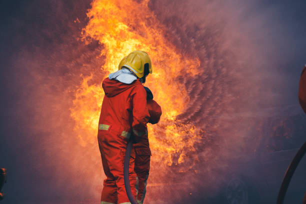 istock Firefighter Rescue training in fire fighting extinguisher. Firefighter fighting with flame using fire hose chemical water foam spray engine. Fireman wear hard hat, safety suit uniform for protection 1439365060