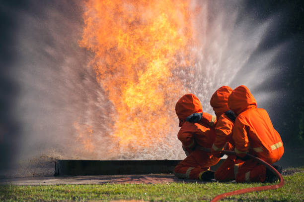 istock Firefighter Rescue training in fire fighting extinguisher. Firefighter fighting with flame using fire hose chemical water foam spray engine. Fireman wear hard hat, safety suit uniform for protection 1439365627