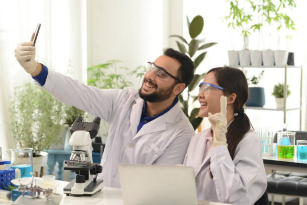 2人の科学者または化学者が実験室でスマートフォンで自撮り写真を撮ります。 - scientist research group of people analyzing ストックフォトと画像