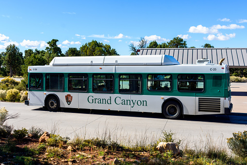 Grand Canyon Shuttle Bus white with a green stripe parked at National Park Visitor Center. Side view. - Arizona, USA - October, 2022