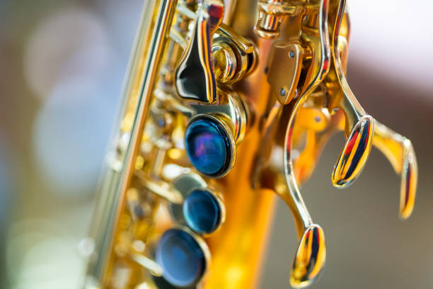 A captivating image focusing on the bottom part of an alto saxophone, captured with a wide aperture. The beautiful bokeh effect amidst a natural setting highlights the intricate details and elegance
