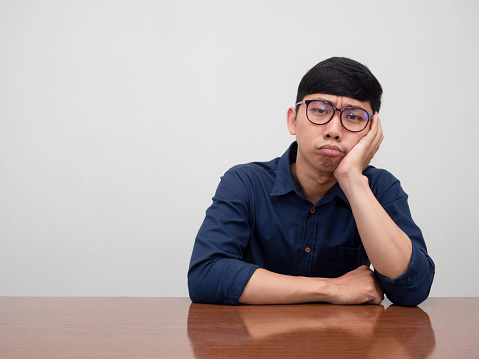 Asian businessman wear glasses sit at the table feels bored