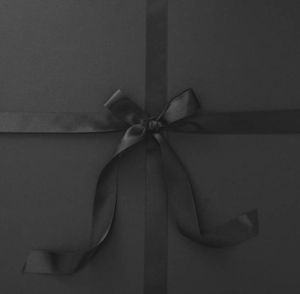 istock Black Friday sales. Satin ribbon and bow on black background overhead 1439388768