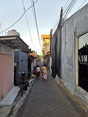 Local people walking in a narrow alley in Seminyak, a famous tourist area on the west coast of Bali, Indonesia