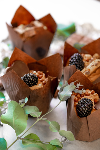 Appetizing muffin with blackberry and eucalyptus leaves on silver foil.Chocolate dessert. Assorted sweet table. Sweets and desserts. Baked goods and desserts