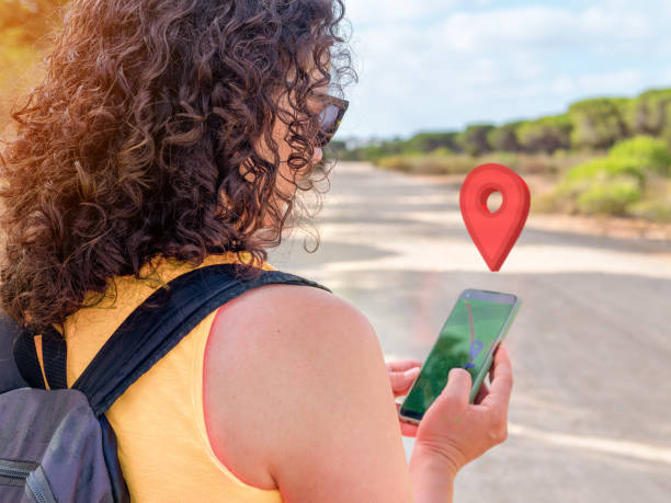 istock Woman's back with gps location on a cell phone while walking or hiking in the mountains or forest. 1439393506