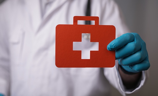 A papercut of a medical cross sign in the hands of a doctor
