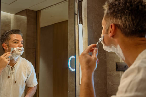 istock Man shaving face in bathroom mirror 1439394982