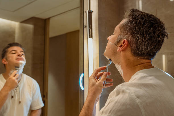 istock Man shaving face in bathroom mirror 1439395191
