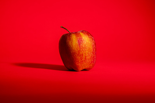 Red apple on a red background, conceptual image