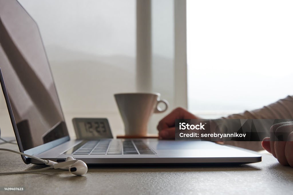 Man working from home on the desk with laptop and coffee mug Man working from home on the desk with laptop and coffee mug. Freelancers and business concepts Digital Clock Stock Photo