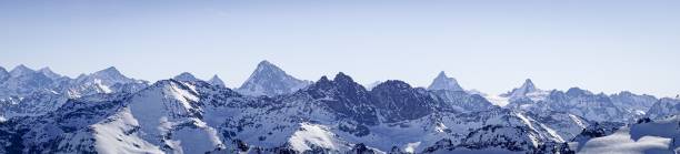 istock Beautiful panoramic shot of snow covered mountain ranges under a clear blue sky 1439408717