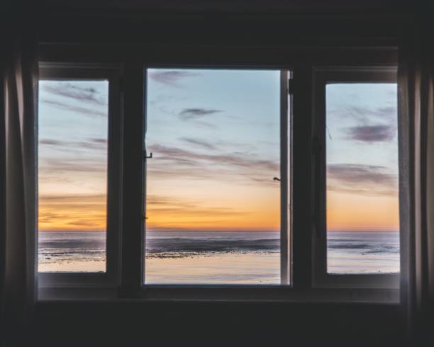 A three-paneled window with a beautiful view of the sunset outside