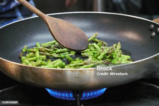 Closeup Of Asparagus Sauteed In A Nonstick Pan With A Wooden Ladle Stock Photo - Download Image Now