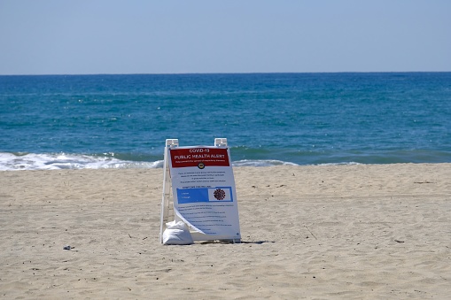 carlsbad, United States – March 27, 2020: Empty beach with covid-19 health hazard sign.