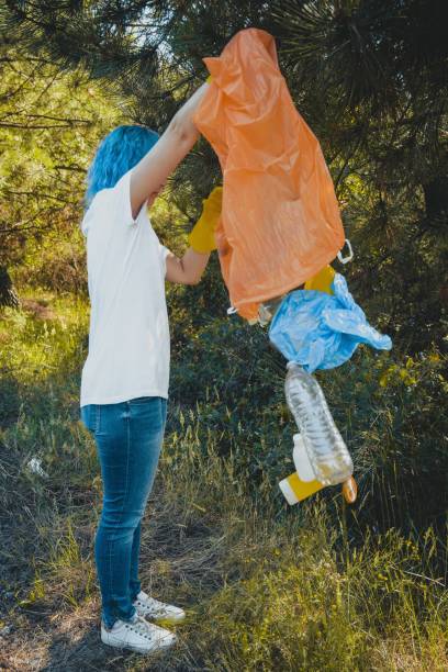 istock Young female collecting trash and putting in plastic garbage bag - environmental pollution concept 1439414901