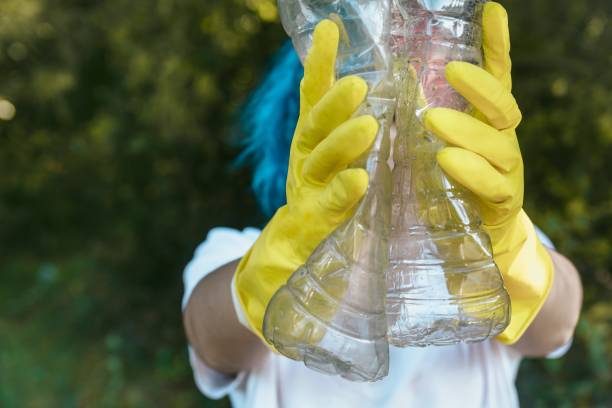 istock Female wearing gloves holding recyclable plastic bottles - plastic pollution concept 1439415122