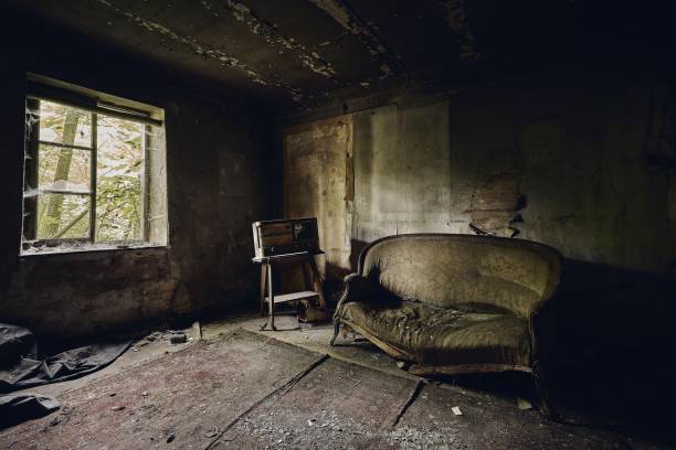 istock Abandoned room with a broken sofa on an aged floor and with a broken window on the wall 1439416603