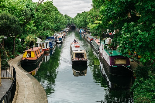 London, United Kingdom – June 08, 2017: A narrow boat makes its way along Regent's Canal, one of London waterways, United Kingdom.