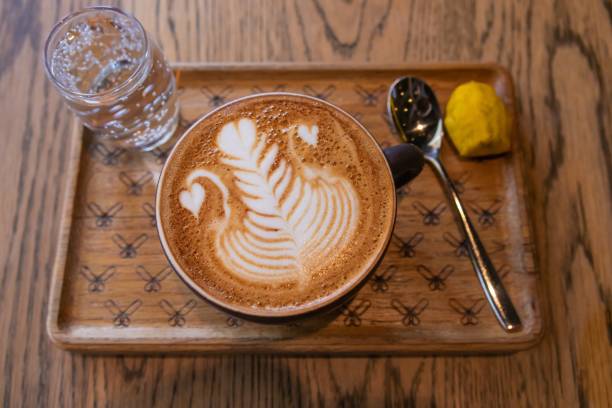 plan rapproché d’un plateau en bois avec un verre d’eau gazeuse et une tasse de cappuccino - latte machiatto photos et images de collection