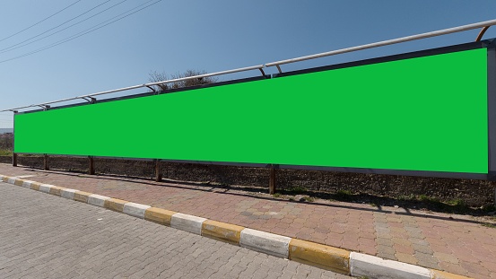 A long green screen for ads at the side of a road, an excellent space for your text