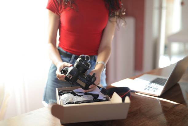 istock Woman holding a camera with a notebook on the table 1439419039