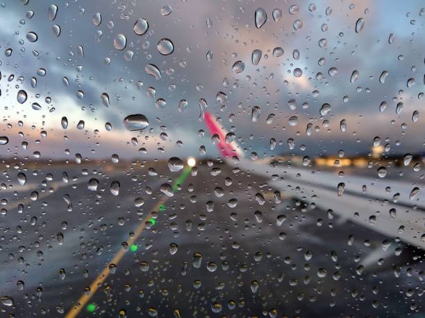 vista sfocata di una pista aeroportuale attraverso il finestrino di un aereo con gocce di pioggia - runway airport rain wet foto e immagini stock