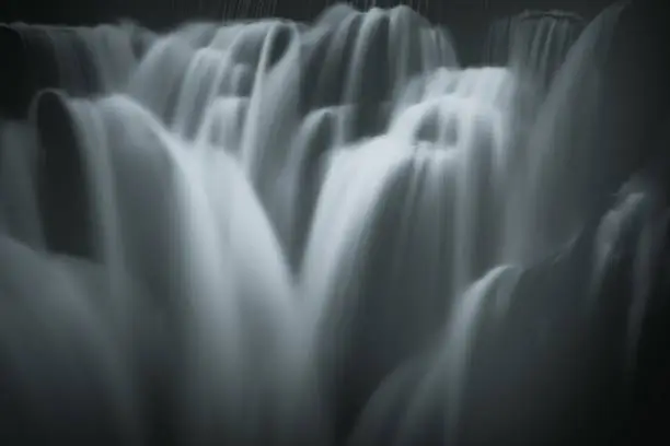 Photo of Greyscale closeup shot of the pouring foamy cascades of a waterfall