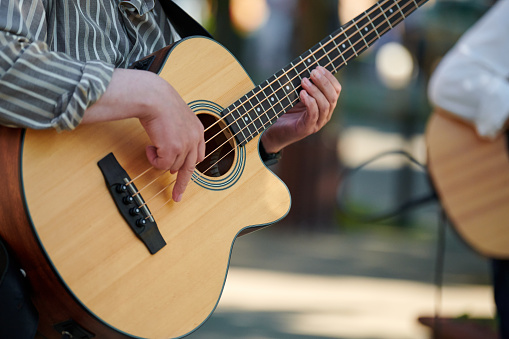 Man playing acoustic bass guitar at outdoor event, close up view to guitar neck