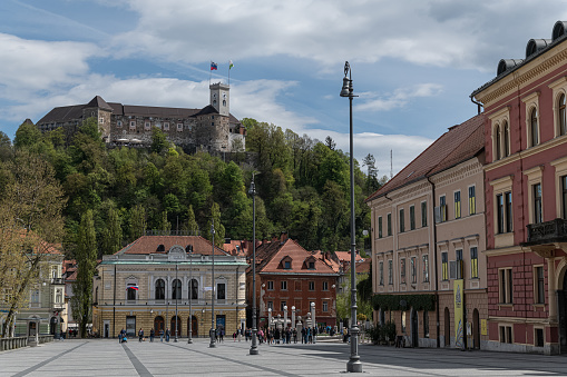 Ljubljana University Square with Ljubljana Castle perched upon a hill in the background on a sunny spring day.