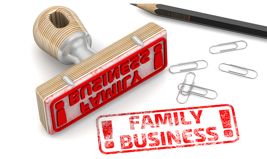 The stamp and a red imprint with text: FAMILY BUSINESS on a white surface with pencil and clips. 3D illustration