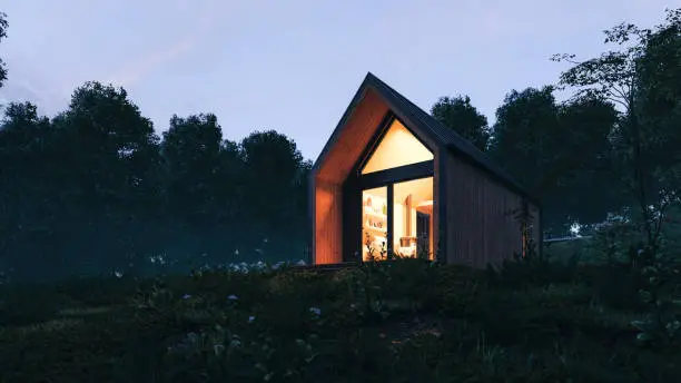 Modern Scandinavian style wooden tiny house in forest at night. A new form of living philosophy to reduce ecological footprint.