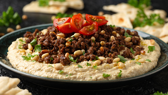 Hummus with spiced ground beef, olive oil, tomatoes and toasted pine nuts