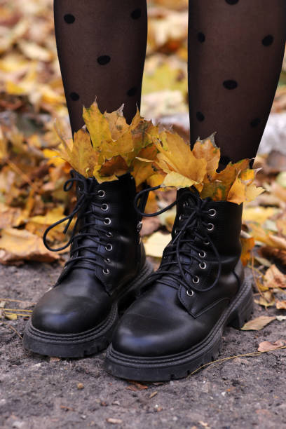 istock women's boots with autumn leaves, fall concept. Vertical Orientation 1439440016