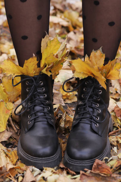 istock women's boots with autumn leaves, fall concept. Vertical Orientation 1439440019