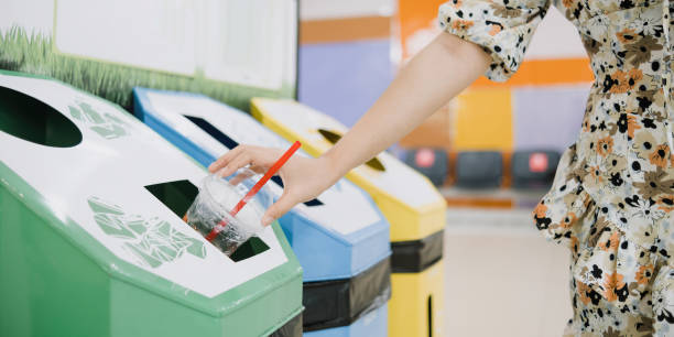 女性はプラスチックカップをごみ箱に落とし、地球環境保護と持続可能性のコンセプト。 - 捨てる ストックフォトと画像