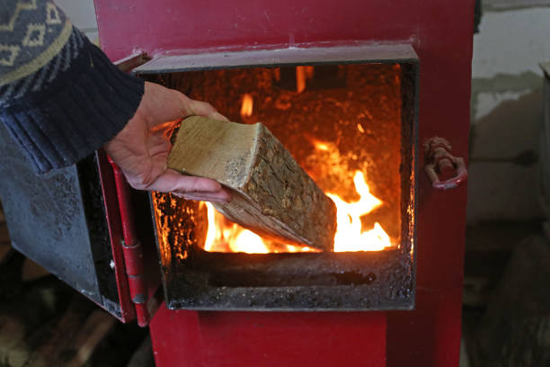 A man puts firewood in the heating stove.