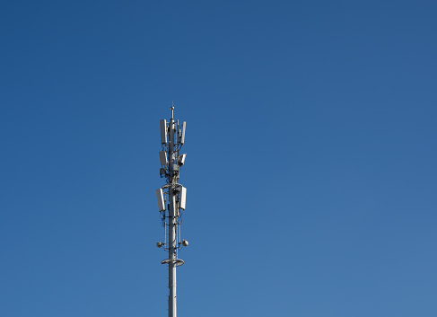 Mobile telephony signal repeater and base station antenna next to a green tree, selective focus