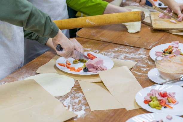 istock Culinary training. Children's hands with knife cut vegetables and sausage on white table plate. 1439447992